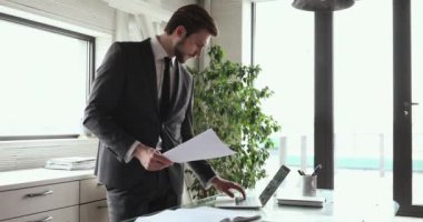 Düşünceli, ciddi bir CEO planlama stratejisi dizüstü bilgisayarla evrak işi yapıyor.