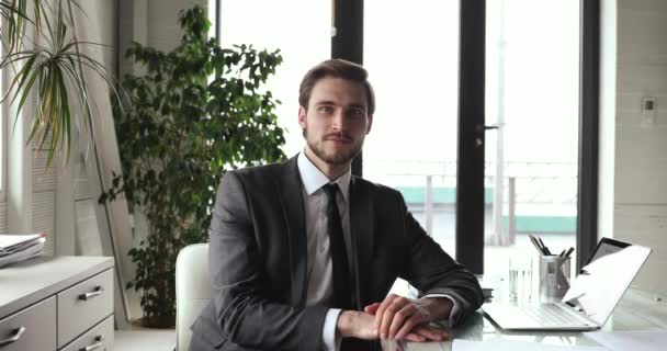 Schöner lächelnder Geschäftsmann im Anzug, der am Arbeitsplatz in die Kamera schaut — Stockvideo