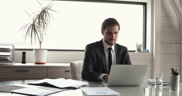 Succesvolle tevreden jonge mannelijke bedrijfsleider ontspannen op de werkplek — Stockvideo