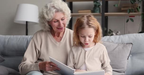 어린 미취학 아동 이 동화를 읽는 것을 듣고 있는 행복 한 할머니. — 비디오