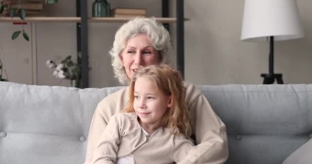 Affectionate volwassen senior oma luisteren naar weinig kleuterschool kind. — Stockvideo