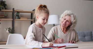 Mutlu küçük kız olgun büyükannenle resim çiziyor..