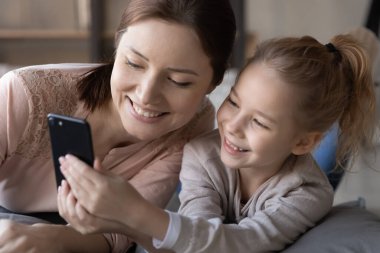 Mutlu bir anne ve küçük bir kız cep telefonu kullanıyor.