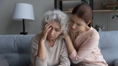 Bakımlı yetişkin kız mutsuz yaşlı anneye destek oluyor.
