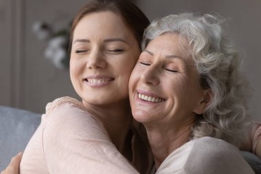 Mutlu yaşlı anne ve büyük kız kucaklaşıp sarılıyorlar.