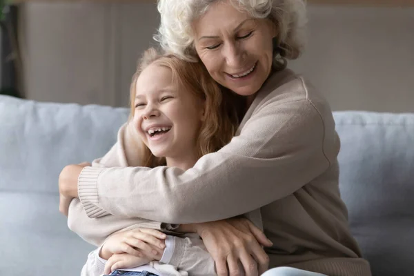 Dolblij grootmoeder omarmen spelen met kleine kleindochter — Stockfoto