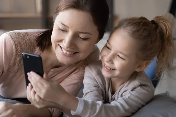 Jovem mãe feliz e filha pequena usando celular — Fotografia de Stock