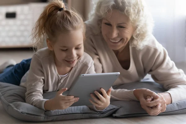 Menina feliz se divertir usando tablet com a avó — Fotografia de Stock