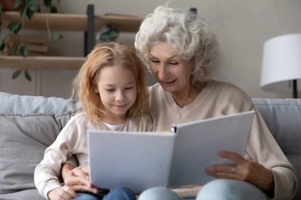 Zorgzame oma lezen boek met kleine kleindochter — Stockfoto