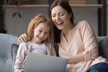 Çok mutlu anne ve küçük kızı birlikte dizüstü bilgisayar kullanıyorlar.