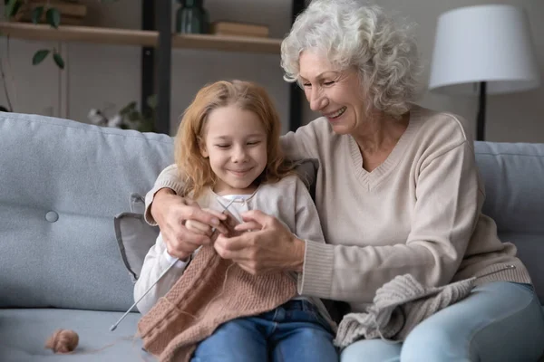 Vårdande äldre mormor lär stickande lilla barnbarn — Stockfoto