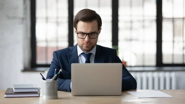 Empresário caucasiano sério usa laptop no escritório — Fotografia de Stock