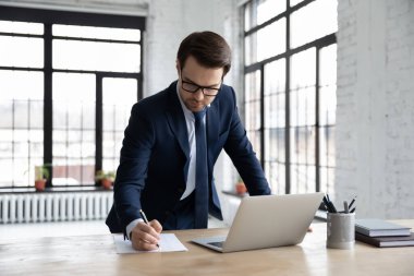 Ciddi iş adamları dizüstü bilgisayarda çalışıp not alıyorlar.