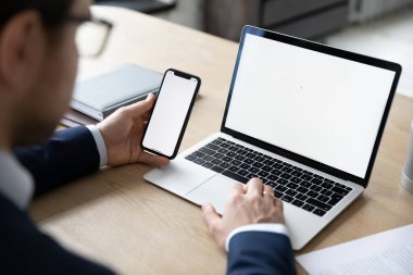 Dizüstü bilgisayarda ve cep telefonunda çalışan erkek işverenin arka görüntüsü