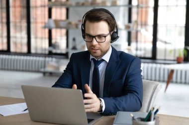 Kulaklık takmış ciddi bir iş adamı laptopta video görüşmesi yapıyor.