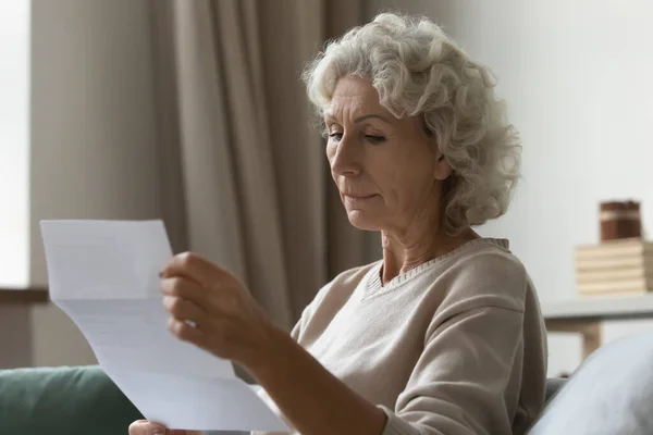 Concentrado mulher madura ler carta postal em casa — Fotografia de Stock
