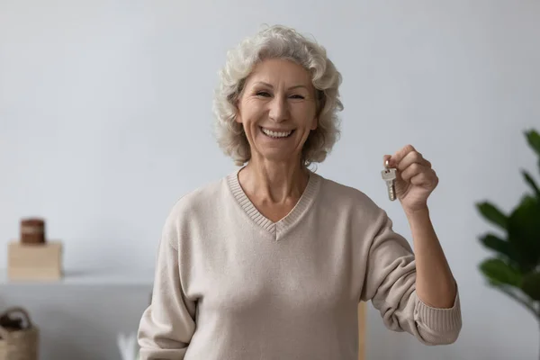 Портрет счастливой пожилой женщины, позирующей с ключами от дома — стоковое фото