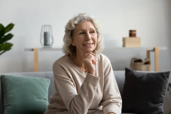 Smiling mature woman look in distance thinking