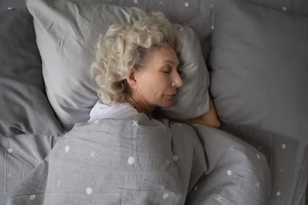 Tenang wanita senior tidur di tempat tidur rumah yang nyaman — Stok Foto