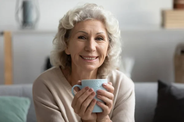 Porträt einer lächelnden reifen Frau, die heißen Tee genießt — Stockfoto