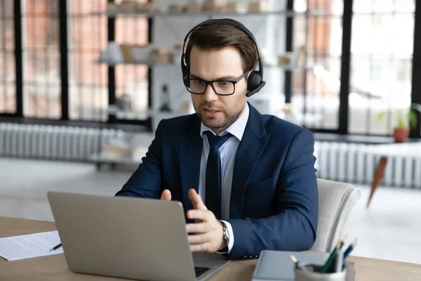 Seriöser Geschäftsmann im Headset-Gespräch bei Videotelefonie auf Laptop — Stockfoto