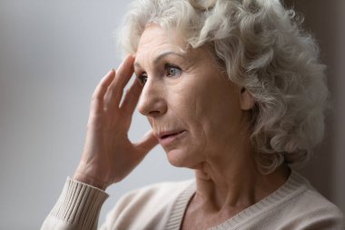 Unhappy elderly woman lost in thoughts in retirement house clipart