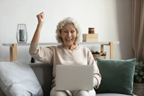 Emocionado mujer mayor obtener un buen mensaje inesperado en el ordenador portátil — Foto de Stock