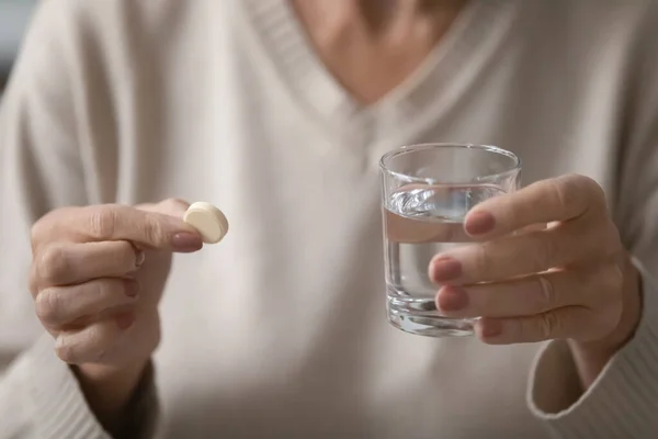 Close up of older woman having pill with water — Stock Photo, Image