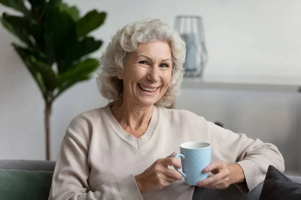 Retrato de mujer mayor sonriente relajarse en el sofá en casa — Foto de Stock