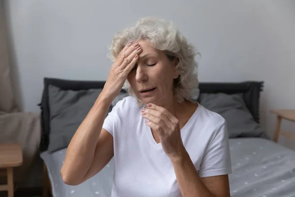 Нездоровая пожилая женщина страдает мигренью дома — стоковое фото