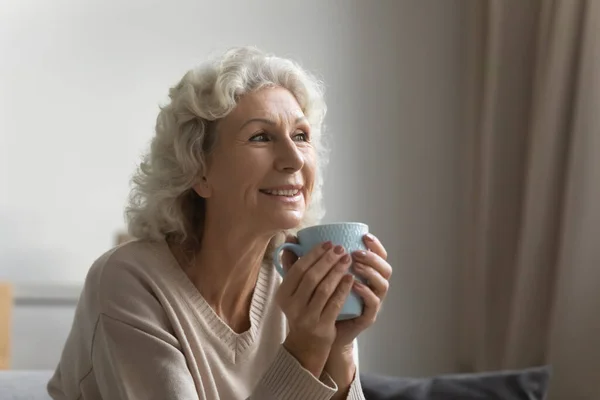 Feliz mujer mayor beber café pensando en casa — Foto de Stock
