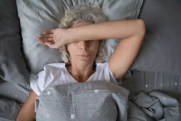 Yorgun, olgun bir kadının yatakta uyumasının en iyi görüntüsü. — Stok fotoğraf