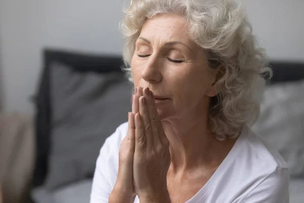 Religious old woman praying to God at home — Stock Photo, Image