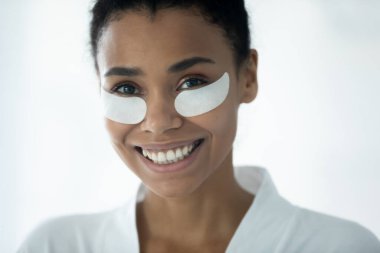 Göz bantları altında gülümseyen Afrikalı Amerikalı kadın.