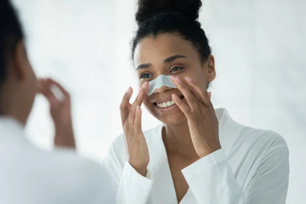 Spegelreflektion Afrikansk amerikansk kvinna applicera anti pormaskar patch — Stockfoto