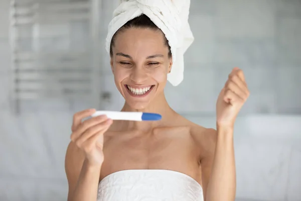 Head shot happy young woman looking at pregnancy test