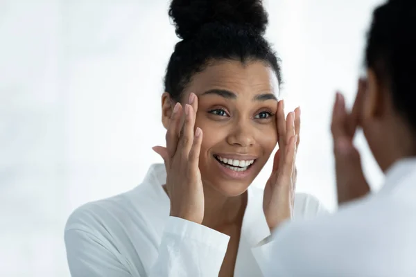 Zrcadlový odraz s úsměvem Afroameričanka dělá masáž obličeje — Stock fotografie