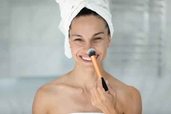 Head shot portrait smiling woman using cosmetics brush, touching nose — Stock Photo, Image