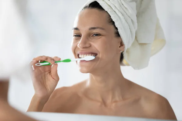 Head shot beautiful woman brushing teeth, looking in mirror — Stock Photo, Image