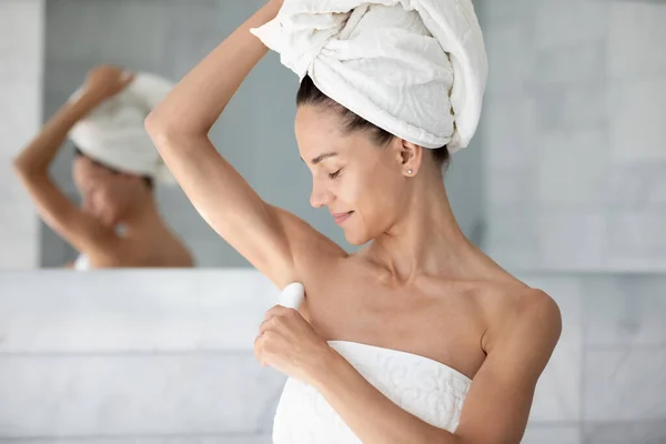Satisfied young woman applying antiperspirant on armpit after shower — Stock Photo, Image