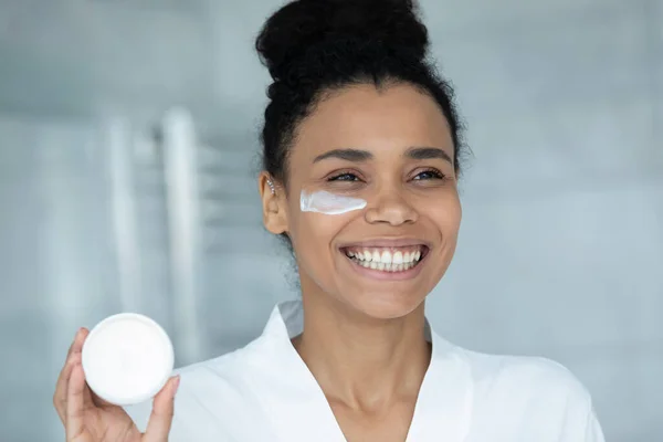 Close up smiling African American woman holding face cream jar — Stock Photo, Image