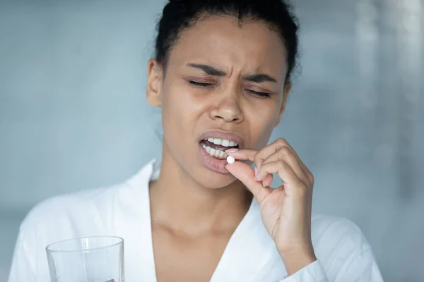 Close up unhealthy exhausted African American woman taking pill — Stock Photo, Image