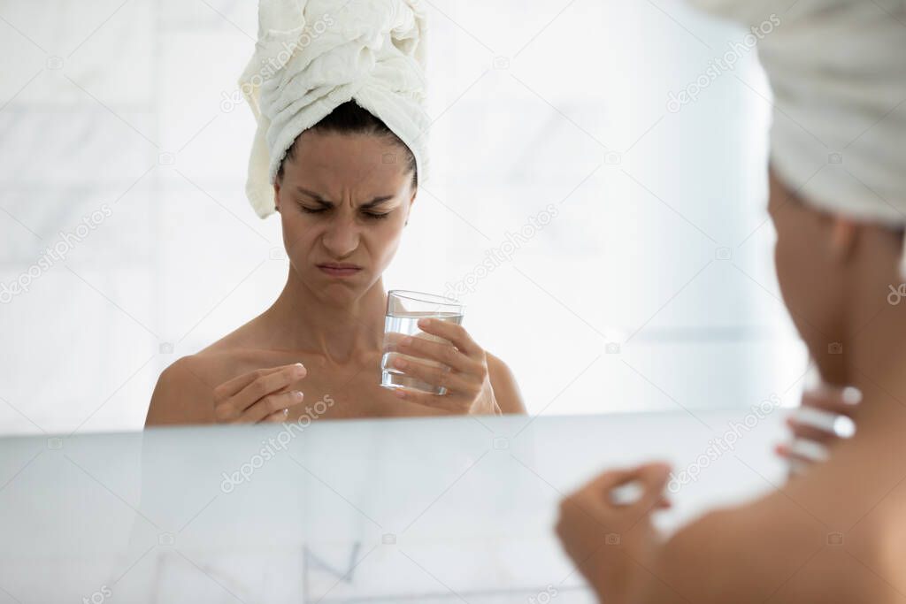 Mirror reflection unhealthy woman holding pill and glass of water