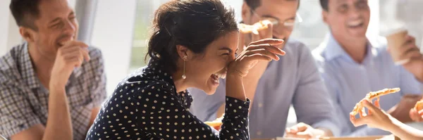 Laughing indian businesswoman eating pizza enjoy lunch together with colleagues — Stock Photo, Image