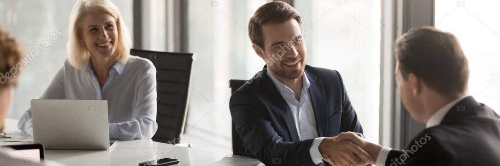 Happy business partners shake hands closing deal during negotiations