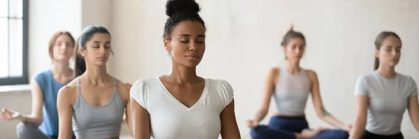 Entrenadora africana lidera sesión de meditación de yoga en grupo en interiores — Foto de Stock