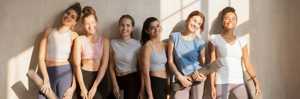 Multiracial girls resting after workout holding mats looking at camera — Stock Photo, Image