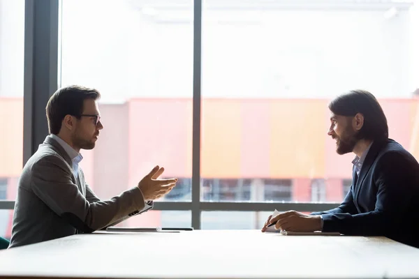 Vista lateral dois empresários resolvem questões atuais conversando durante as negociações — Fotografia de Stock