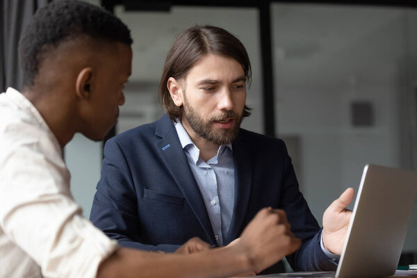 Caucasian mentor teach african intern explaining corporate app in office