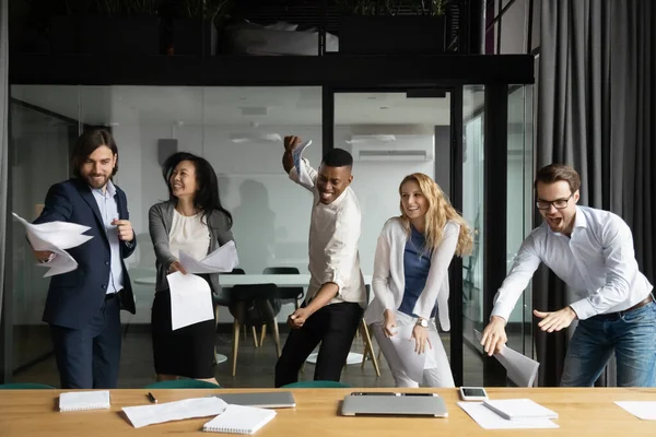 Mångsidig personal dansar runt på arbetsplatsen firar seger — Stockfoto